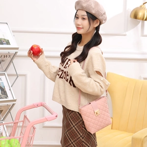 Pink quilted bucket shoulder bag with gold twist lock in a stylish home setting