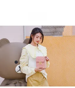 Asian model carrying a pink crocodile pattern mini phone bag with chain strap