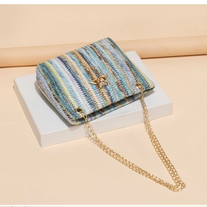 Close-up of colorful straw woven bucket bag featuring gold bee buckle and chain strap