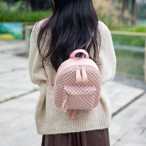 Outdoor shot of a pink mini backpack with circular patterns on a beige sweater model