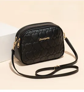Detail of black heart-quilted PU camera bag with double zippers and gold hardware