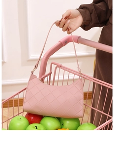 Detailed view of pink quilted baguette bag with gold metal hardware and diamond stitching