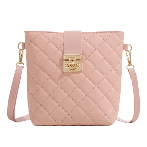 Pink quilted bucket crossbody bag with gold buckle clasp and detachable strap on white background