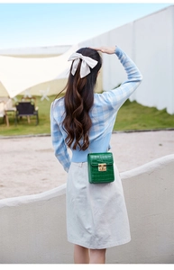 Green crocodile-textured mini crossbody phone bag shown on a model in an outdoor setting