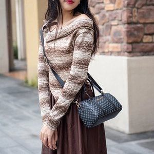 Classic checkered Boston bag with top handles and gold hardware shown on a model