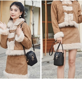 Vertical black matte leather phone bag with golden bear charm shown in street style