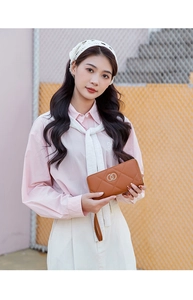 Close-up of a brown quilted long wallet with golden double ring buckle and wristlet strap