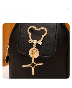 Detail of black leather bag featuring gold mouse-shaped pendant and starry hardware