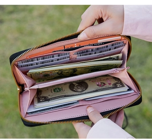 Detail view of long quilted wallet showing black leather exterior and pink multi-slot interior