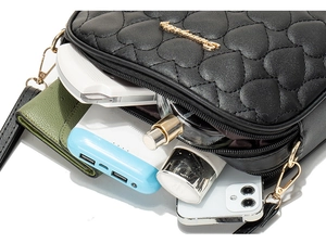 Interior view of black heart-quilted camera bag showing storage for phone and wallet