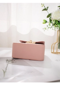 Detail view of the bottom of a stylish pink small crossbody bag with gold hardware