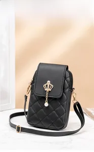 Detail of black quilted leather phone bag featuring a metal crown and pearl pendant charm
