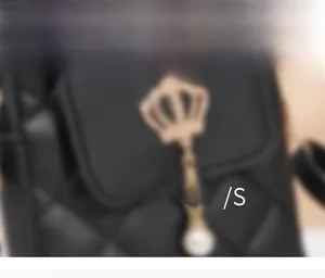 Detailed close-up of quilted handbag with golden crown charm and white pearl accent