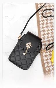 Detail of black quilted crossbody phone bag with gold crown charm and pearl pendant