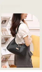 Detail of black woven leather underarm bag with gold metal plate on a shoulder strap