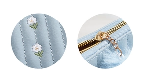 Close-up of light blue mini purse with white floral embroidery and gold zipper detail