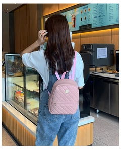 Vista posteriore di una modella con mini zaino rosa trapuntato in un caffè