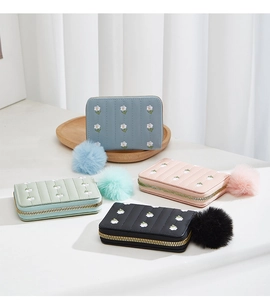 Detailed embroidery of small white flowers on colorful mini zip wallets with pompom charms