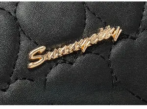 Detail of black quilted heart texture and golden metal logo on the faux leather bag