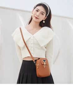Close-up of warm brown leather phone bag with cartoon silhouette and gold star pendant