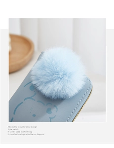 Détail du petit sac bleu avec motif ours, pompon peluche et bandoulière réglable