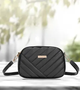 Close-up of black quilted camera bag with gold metal plate and zipper detail