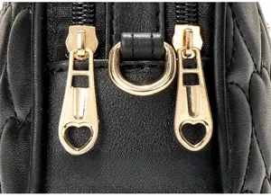 Detail of gold heart-shaped metal zipper pulls on black quilted leather camera bag