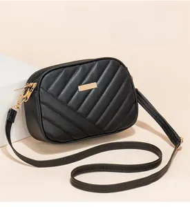 Close-up of black quilted PU leather shoulder bag with rectangular gold metal plaque