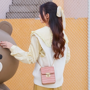 Pink crocodile pattern mini crossbody bag with gold chain strap worn by a model
