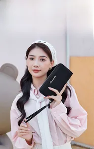 Close-up of black lychee leather long wallet with golden logo and wrist strap detail