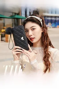 Chic black quilted clutch wallet featuring gold butterfly hardware and pom-pom charm