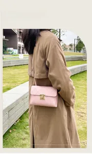 Pink quilted crossbody bag with gold buckle detail worn by a model in a beige coat