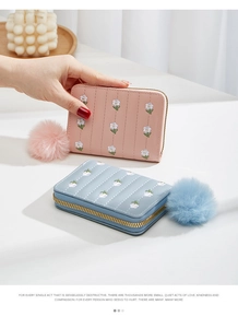 Close-up of mini quilted PU leather wallet with floral embroidery and pompom charm