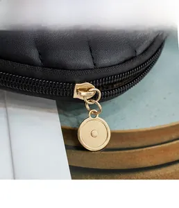 Detail of smooth gold circular hardware zipper pull on black quilted leather handbag
