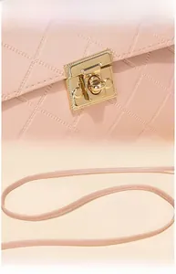 Detail of pink quilted shoulder bag featuring a gold square lock and leather strap