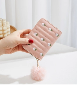 Detailed view of pink floral embroidered mini wallet with soft plush ball and zipper