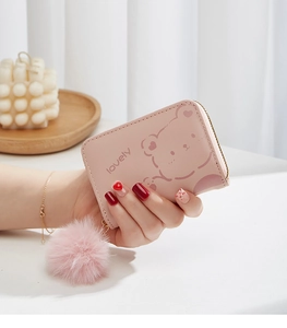 Porte-monnaie rose à motif ours avec pendentif en peluche tenu à la main en détail