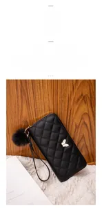 Close-up of black quilted leather long wallet with golden butterfly buckle and pompom charm