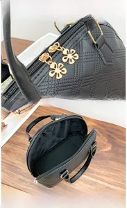 Detail view of black quilted Boston bag featuring golden floral zipper and interior space