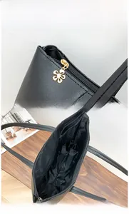 Detail of black leather tote bag showing gold flower zipper and spacious interior compartment
