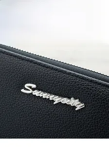 Close-up of black lychee grain leather wallet with silver Sunnycity metal logo