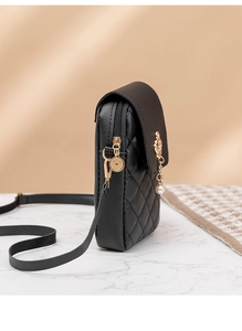 Detail of embroidered black crossbody phone bag with gold crown and pearl pendant