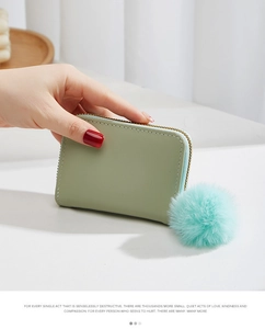 Détail d'un porte-monnaie en cuir PU vert clair avec pompon bleu et surpiqûres blanches