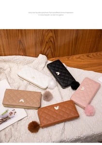 Detailed view of quilted long wallets with butterfly accents and matching faux fur pom-poms