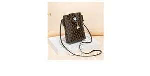 Detail of coffee brown geometric phone bag with cat-shaped buckle and pearl tassel