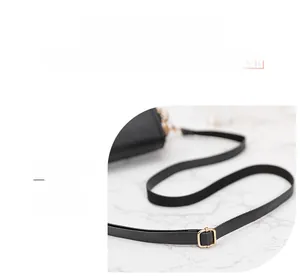 Detail of black faux leather adjustable shoulder strap with gold metal buckle on marble