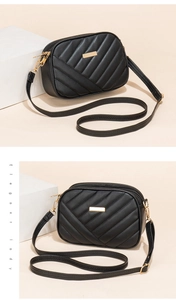 Detail of black quilted crossbody camera bag with gold hardware and metal plate