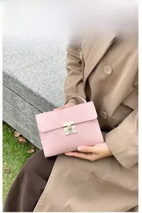 Close-up of pink quilted crossbody bag with gold square buckle and matte leather texture