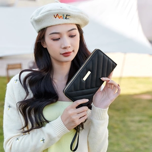 Women's black quilted long wallet with golden metal bar detail and wristlet strap