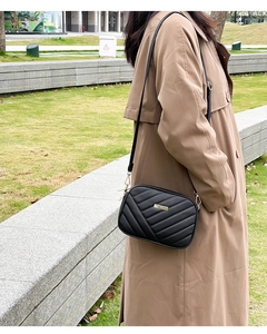 Close-up of black quilted camera bag with V-shaped stitching and golden metal detail